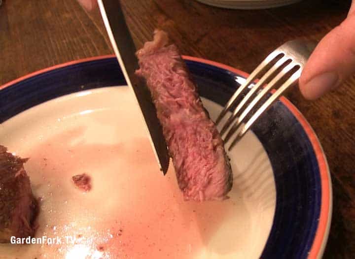 A plate with a fork and knife and steak