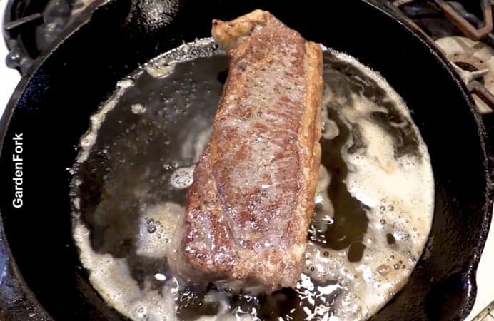 steak cooking in cast iron pan